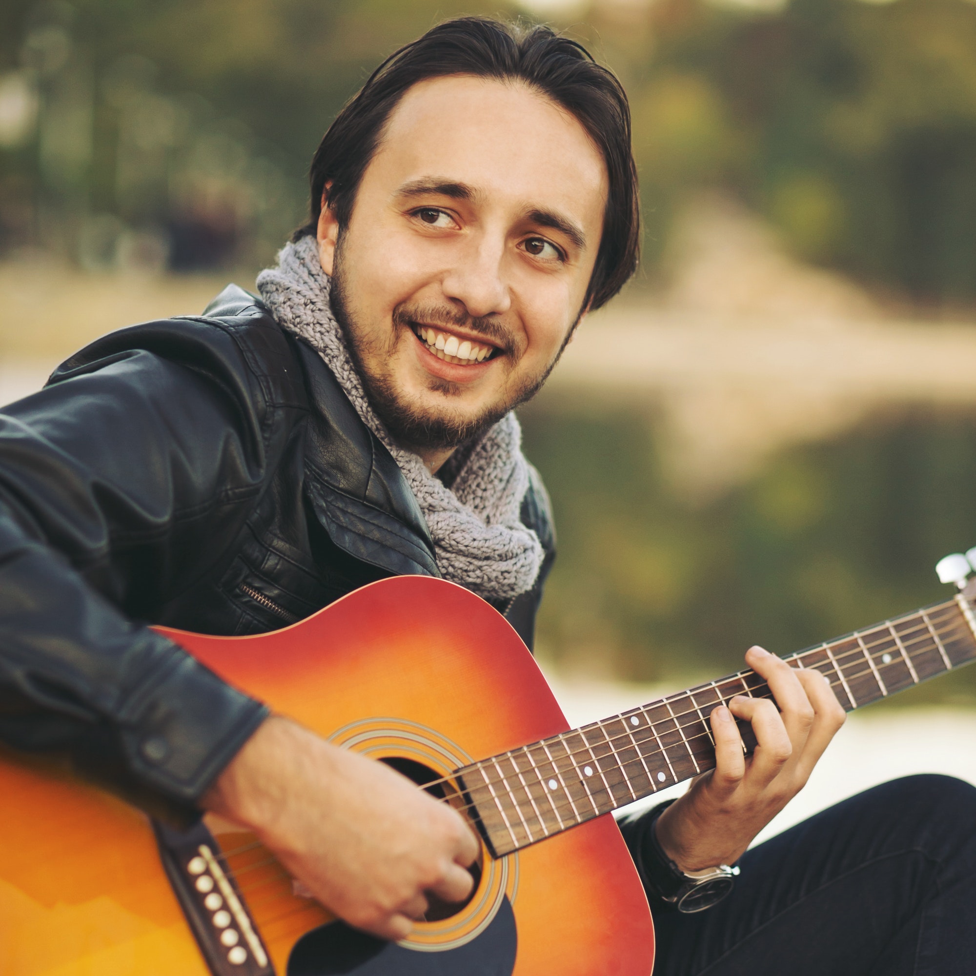 Young man playing on guitar at the lake
